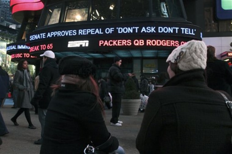 Cassandra Melnikow, foreground left, and her sister Victoria Melnikow,  right, sit in New York's Times Square as news of the Senate approving the repeal of \"Don't Ask Don't Tell\" is displayed outside ABC Television's Times Square studios Saturday Dec. 18, 2010. (AP Photo/Tina Fineberg)